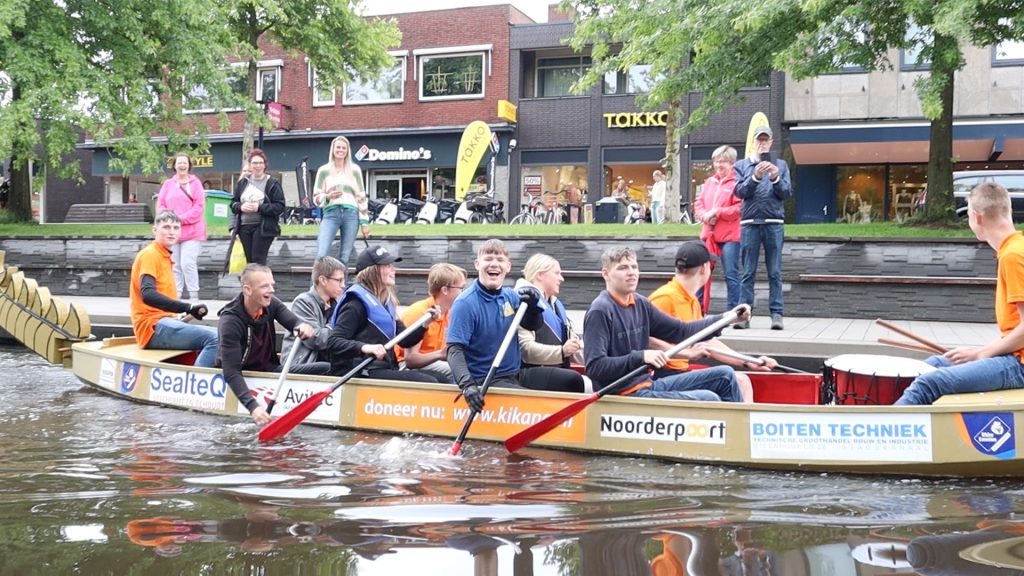 Leerlingen Ubbo Emmius Sportparklaan varen in drakenboot voor Kika van Groningen naar Stadskanaal